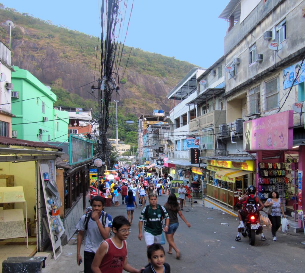 As far as the eye can see, crowds of pedestrians throng a narrow street lined by stores and apartments in Rocinha, the largest favela in Brazil.