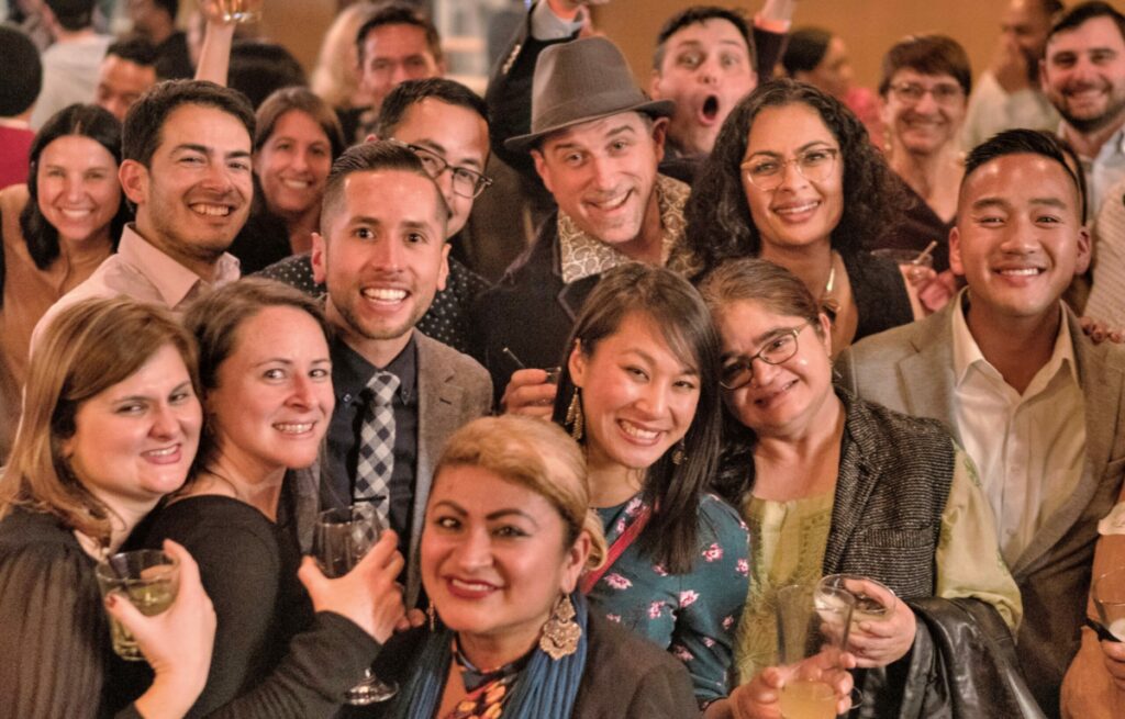 Picture of a group of people gathering at an event and having fun holding drinks.