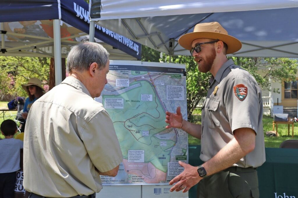 Park Planner Trevor Rice at an outdoor event talking with a participant in front of a map