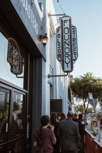 Image of the outside of the Foundry on Folsom Street in San Francisco, CA, with people in line to enter the establishment.