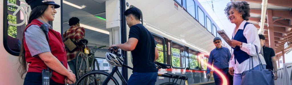 Train attendant welcoming riders boarding a Caltrain bike car