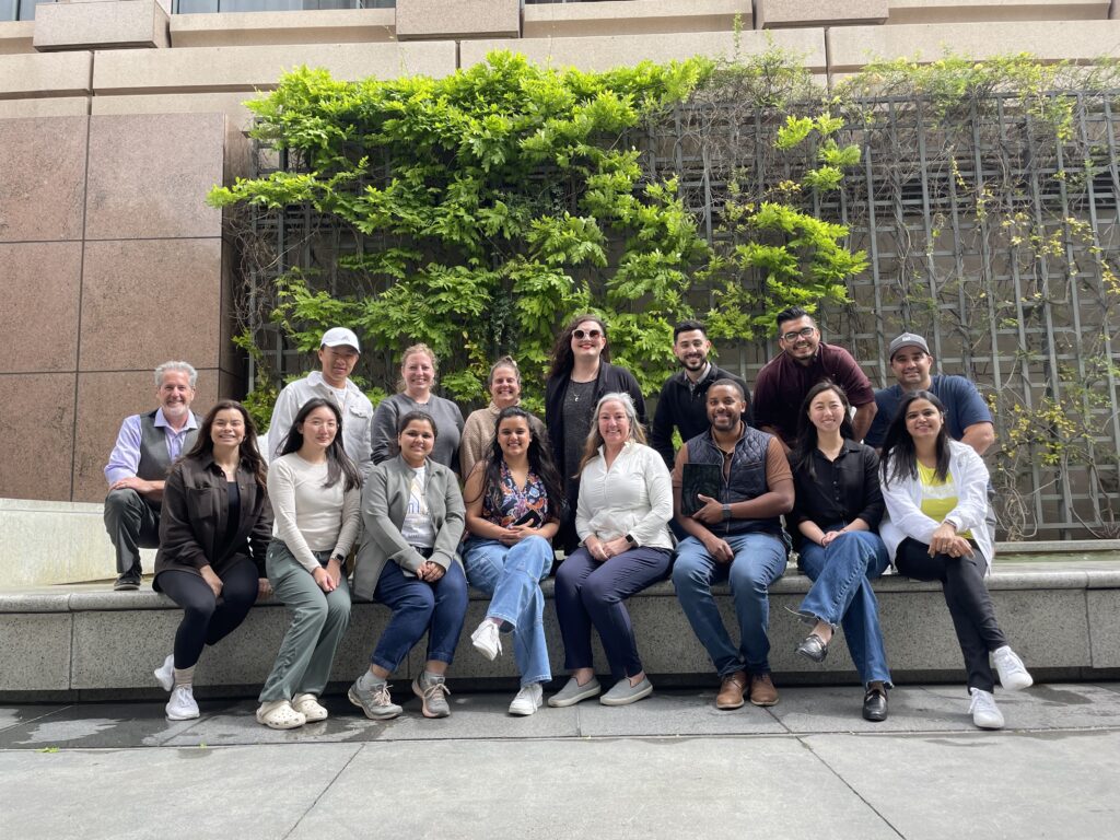 Members of the Capstone Studio Class, Spring 2024 Semester, in front of a fountain and plant wall.