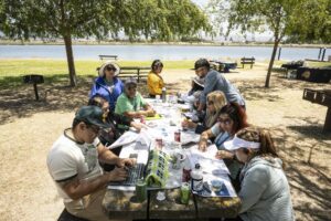 Group of people sitting at around a picnic table working on a project.