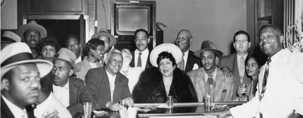 Group photograph of patrons seated around bar at Slim Jenkins Bar and Restaurant, circa 1950s. (Harold Jenkins Photograph collection, MS 11, (African American Museum and Library at Oakland, Oakland Public Library). Group photograph of patrons seated around bar at Slim Jenkins Bar and Restaurant, circa 1950s.