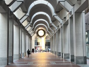 Photo of an outdoor corridor leading to a street with columns on either side and architectural arch for the ceiling.