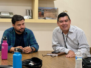 Picture of two men at a conference table smiling and talking.