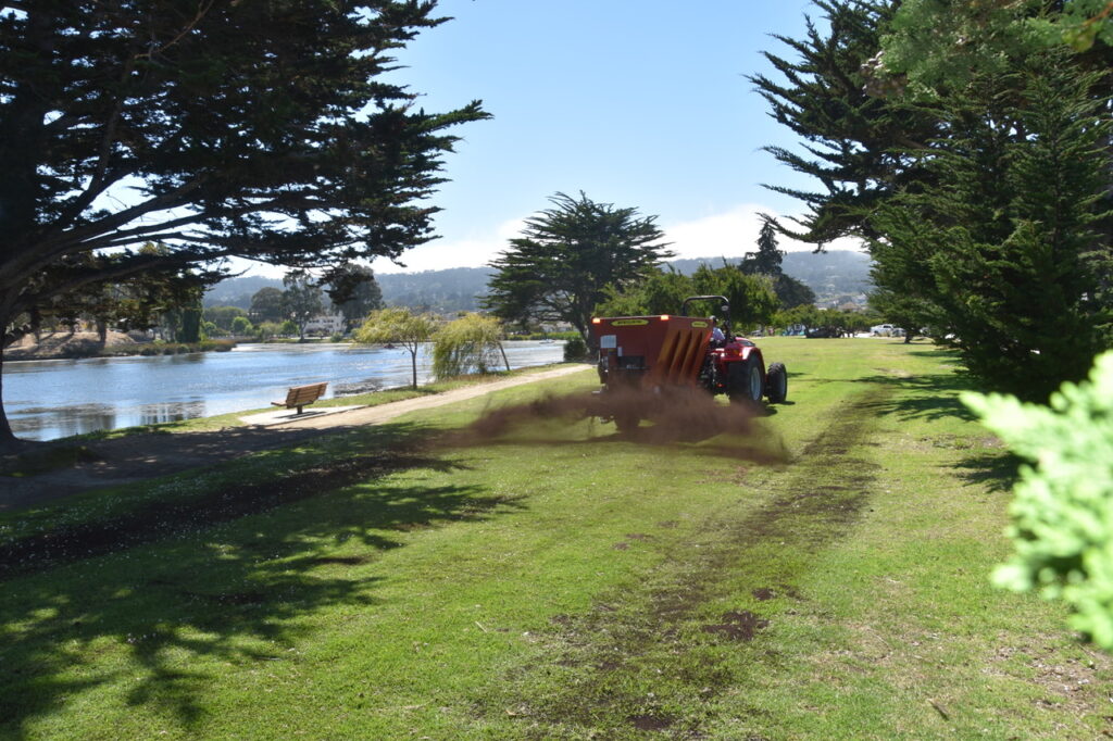 ACP Compost Blower A tractor compost blower spreading compost on a park near water in Monterey, CA