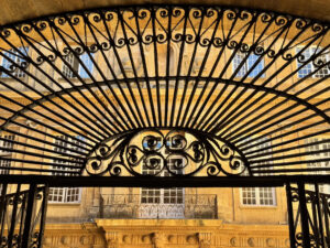 Image of ironwork entry gate to City Hall in Aix En Provence, France with Roman architecture in the background.