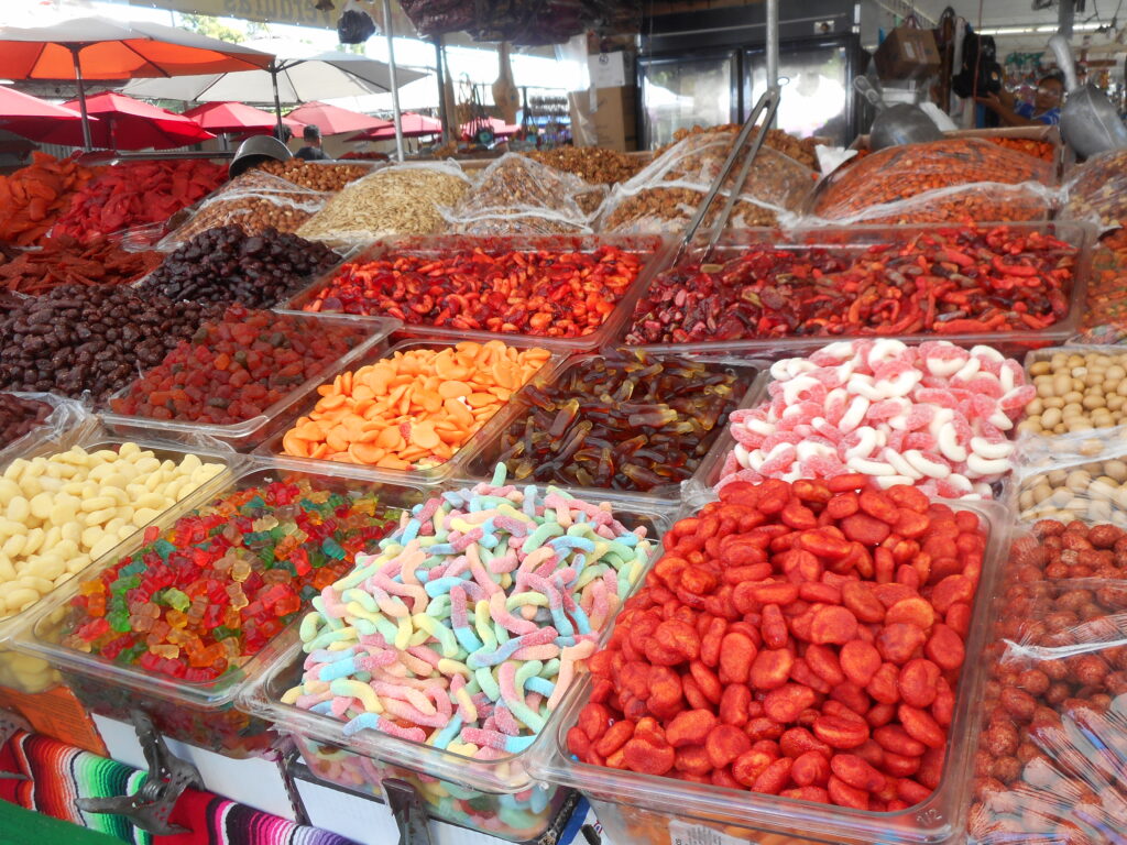 Dulce Vibrant candies and snacks laid out in rectangular display bins at a market stall.