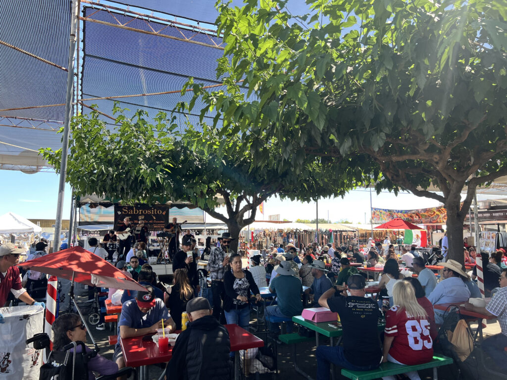LiveMusic Bustling sitting area under a shaded cover at the flea market, featuring live music.