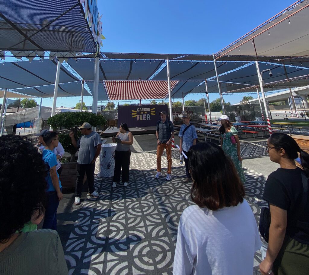 Tour of La Pulga Students circle with community stakeholders at La Pulga during hours of non-operation, before receiving a tour from Berryessa Flea Market Vendors Association (BFVA) leadership.